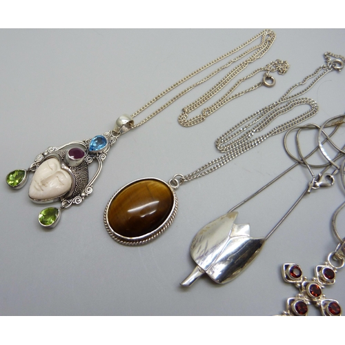 1023 - Four silver and white metal pendants on chains, 37g