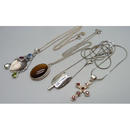 1023 - Four silver and white metal pendants on chains, 37g