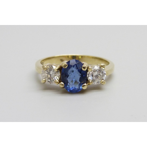 1046 - An 18ct gold ring set with a central blue stone and two diamonds, approximately .90ct diamond weight... 