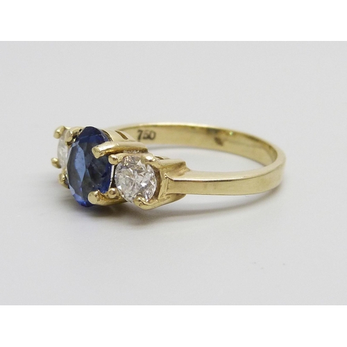 1046 - An 18ct gold ring set with a central blue stone and two diamonds, approximately .90ct diamond weight... 