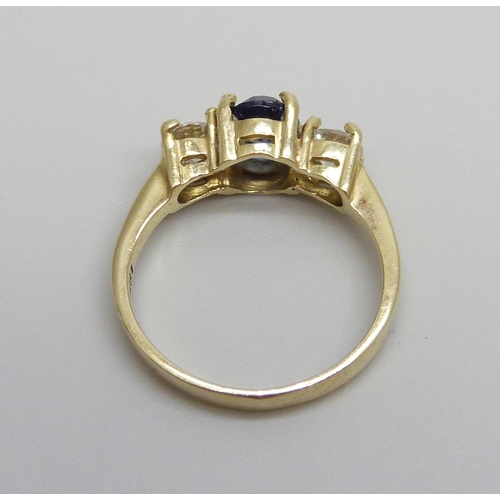 1046 - An 18ct gold ring set with a central blue stone and two diamonds, approximately .90ct diamond weight... 