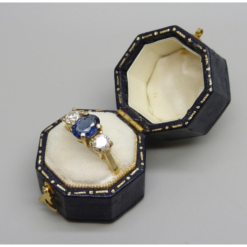 1046 - An 18ct gold ring set with a central blue stone and two diamonds, approximately .90ct diamond weight... 