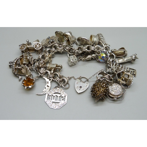 1112 - A large charm bracelet, approximately 26 charms, bracelet and the majority of charms test as silver,... 