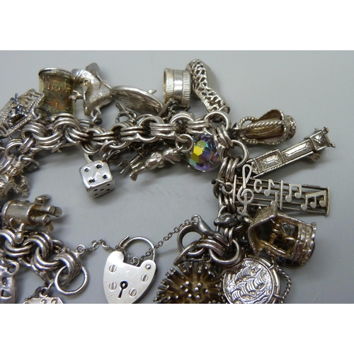 1112 - A large charm bracelet, approximately 26 charms, bracelet and the majority of charms test as silver,... 