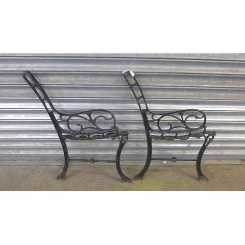 2327 - A pair of cast iron bench ends with a cast metal parasol base