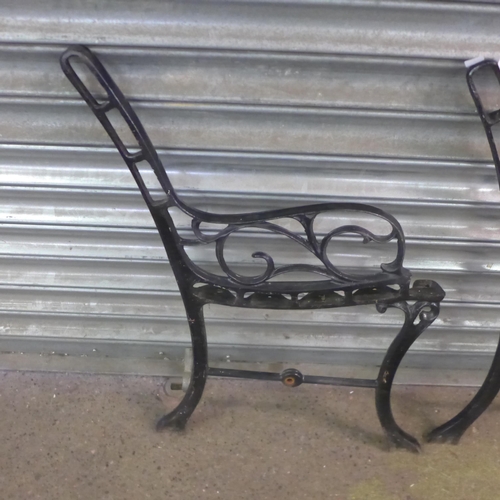 2327 - A pair of cast iron bench ends with a cast metal parasol base