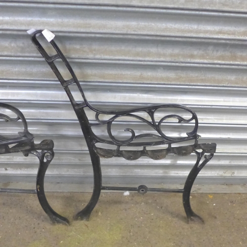 2327 - A pair of cast iron bench ends with a cast metal parasol base