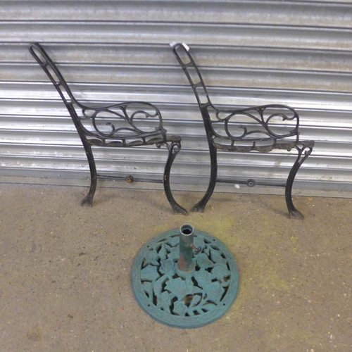 2327 - A pair of cast iron bench ends with a cast metal parasol base