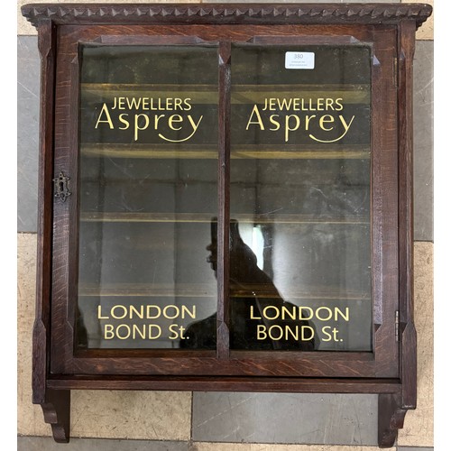 380 - An early 20th Century oak wall hanging display cabinet, bearing Asprey inscription to doors