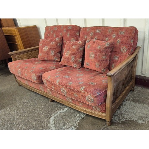 64 - An Ercol ash bergere and fabric upholstered three seater settee