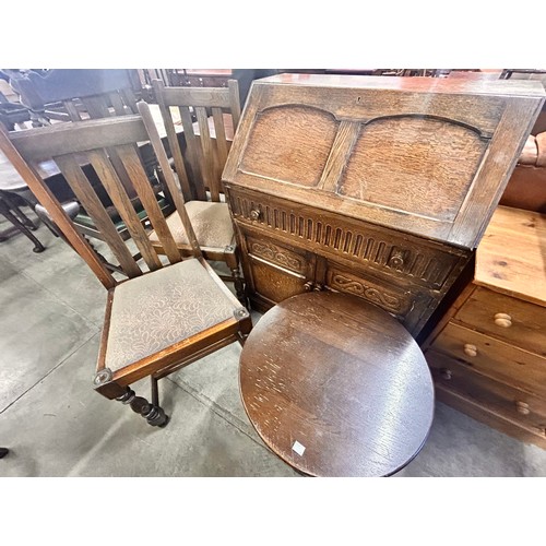 207 - A carved oak bureau, two oak dining chairs and an oak occasional table