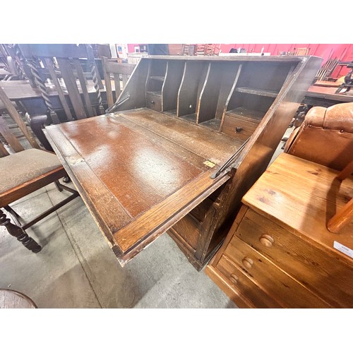 207 - A carved oak bureau, two oak dining chairs and an oak occasional table