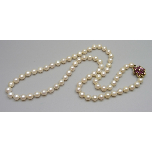 1067 - A string of cultured pearls with 14ct gold and ruby set clasp, 43g, 58cm