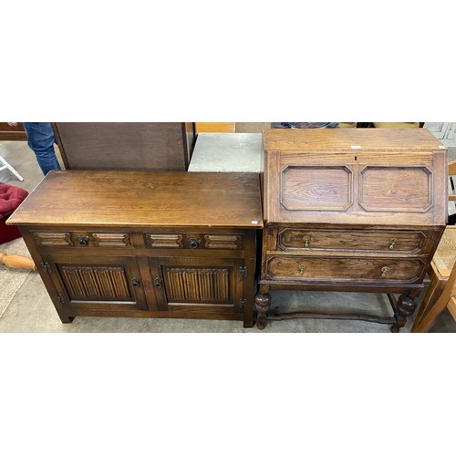 220 - A carved oak bureau and a small oak linenfold sideboard