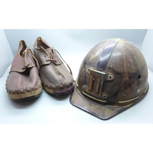 747 - A small child's pit helmet, marked 'A Campbell Head Cradle' and a pair of clogs, marked 1945 and wit... 