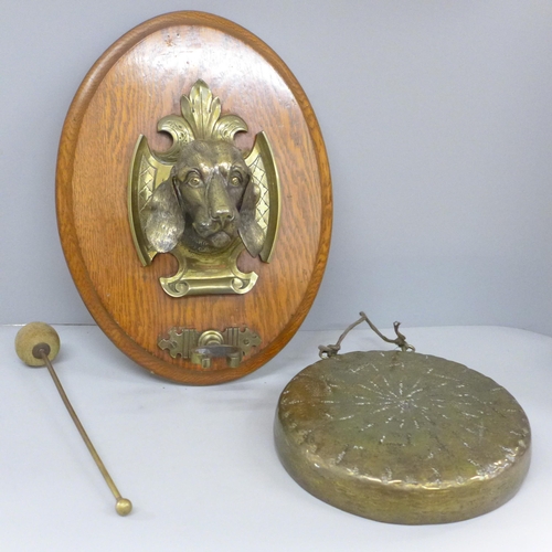 792 - A circa 1900 brass wall gong with dog's head detail mounted on an oak plaque