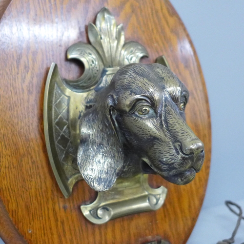 792 - A circa 1900 brass wall gong with dog's head detail mounted on an oak plaque