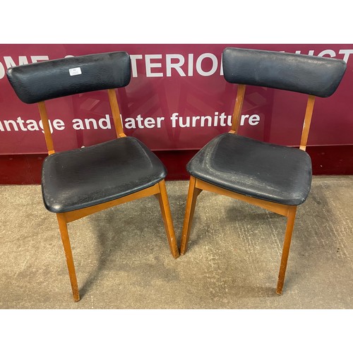 38 - A pair of teak and black vinyl dining chairs