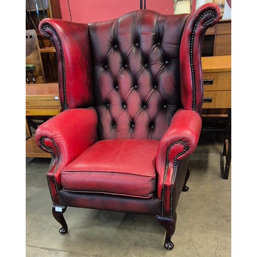 70 - An oxblood red leather Chesterfield wingback armchair