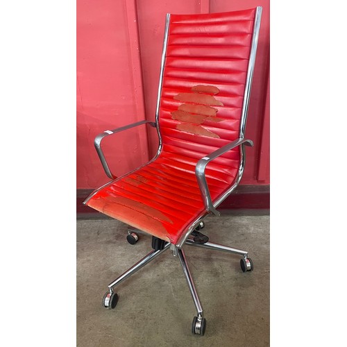 32 - An Eames style chrome and faux red leather revolving desk chair