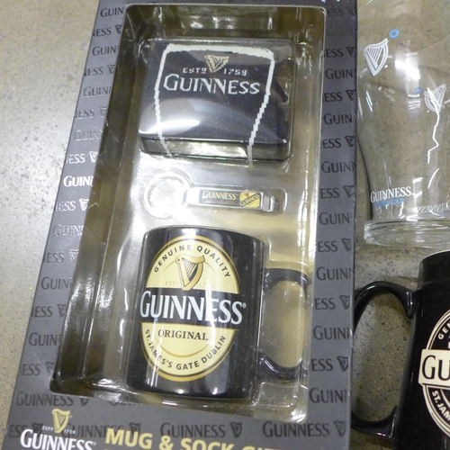 1028 - A box of Guinness memorabilia, three mugs, Notepad & pen, coasters, a sock gift set, etc. **PLEASE N... 