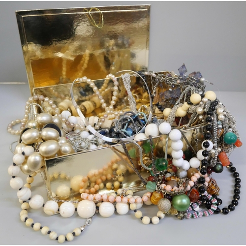 673 - A collection of costume jewellery in a gold coloured box