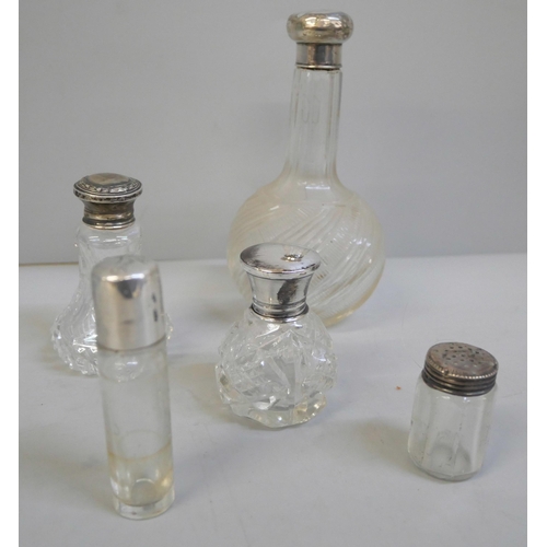 813 - A silver topped cut glass scent bottle, three other silver topped bottles and a bottle with a white ... 