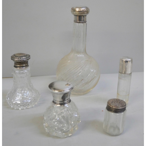 813 - A silver topped cut glass scent bottle, three other silver topped bottles and a bottle with a white ... 