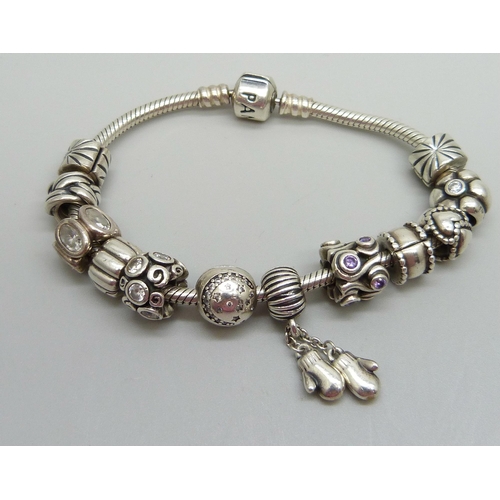 938 - A silver Pandora bracelet with 12 charms and stoppers, 50g