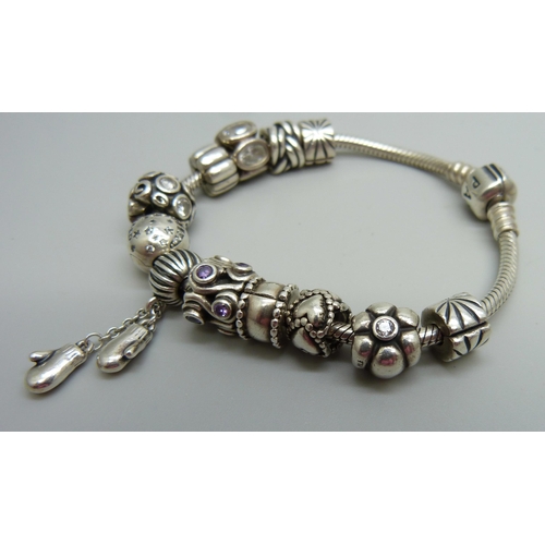 938 - A silver Pandora bracelet with 12 charms and stoppers, 50g