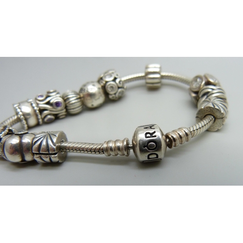 938 - A silver Pandora bracelet with 12 charms and stoppers, 50g