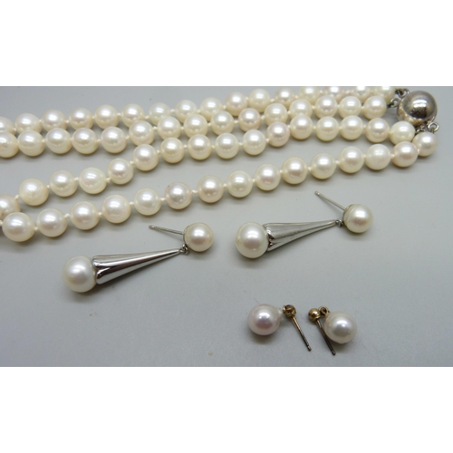 999 - A double row of cultured pearls on a silver clasp, a pair of white metal mounted pearl earrings, and... 