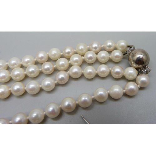 999 - A double row of cultured pearls on a silver clasp, a pair of white metal mounted pearl earrings, and... 