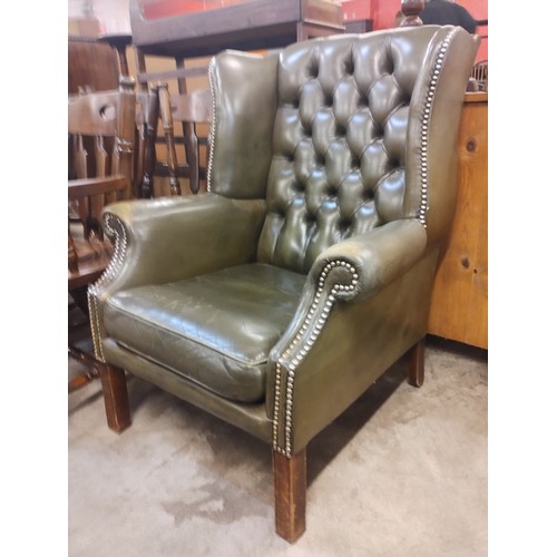 141 - A green leather Chesterfield wingback armchair