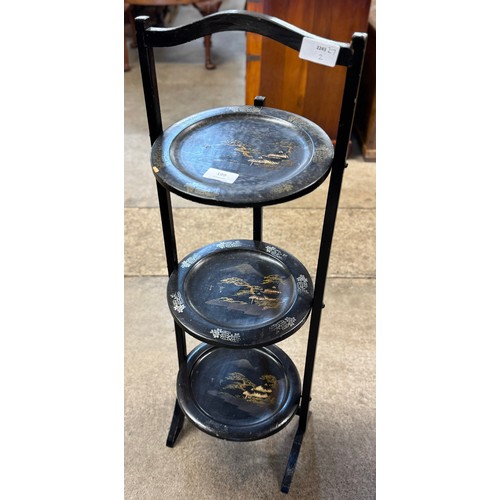 199 - A black Japanned papier mache three tier folding cake stand