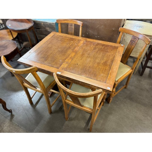 228 - An early 20th Century oak draw leaf dining table and four chairs