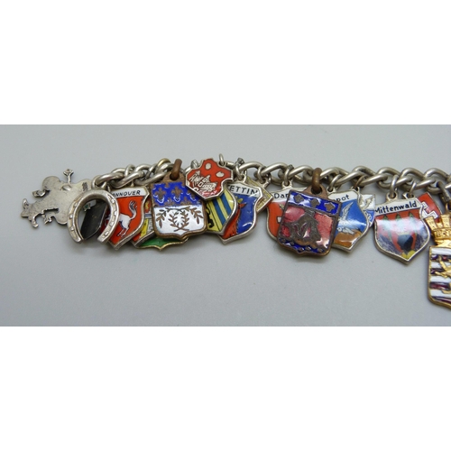 1043 - A white metal charm bracelet with enamel plaque charms including .835 silver and gilt metal, 53g tot... 