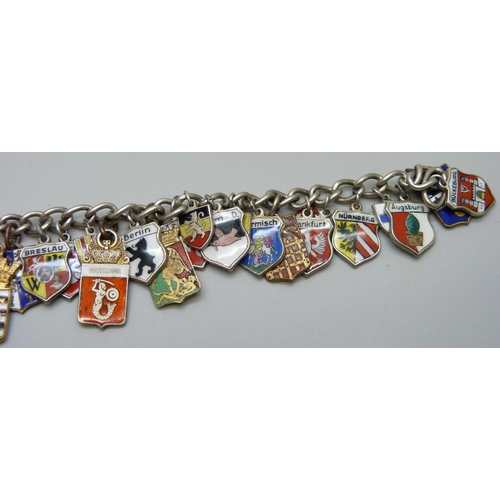 1043 - A white metal charm bracelet with enamel plaque charms including .835 silver and gilt metal, 53g tot... 