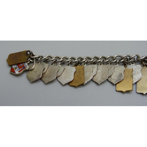 1043 - A white metal charm bracelet with enamel plaque charms including .835 silver and gilt metal, 53g tot... 