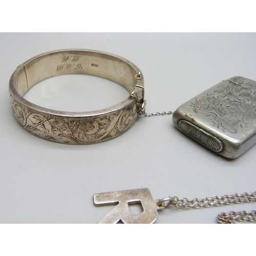 1050 - A silver bangle, 26g, a white metal pocket watch, a plated vesta case, and a silver 'R' pendant on a... 