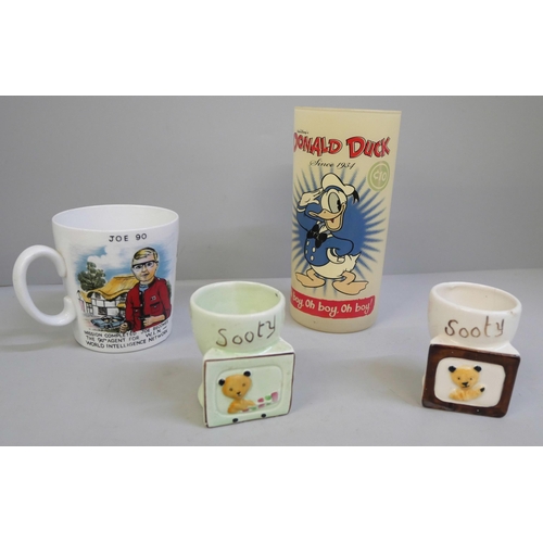 629 - A rare 1950s glass Donald Duck tumbler, a Washington Pottery Joe 90 cup and a pair of novelty Sooty ... 