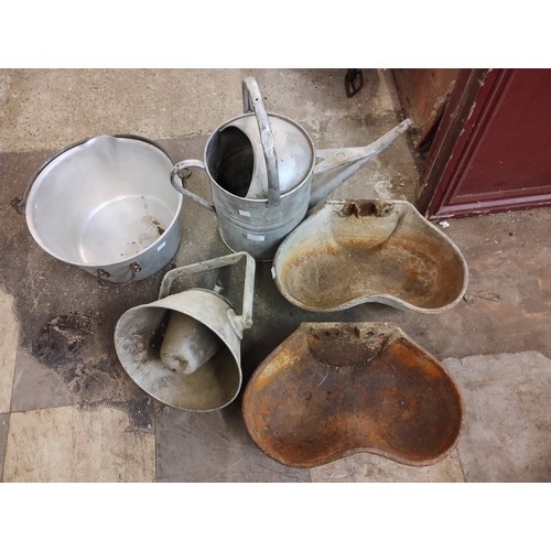 277 - Two cast iron feeders, a galvanised pan, watering can and an Air Raid siren