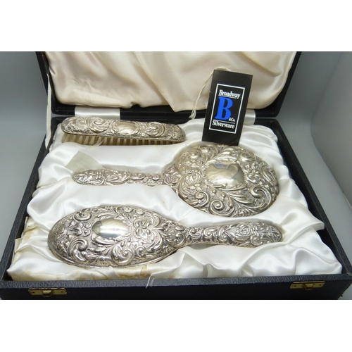 871 - A silver three piece dressing table set with embossed design, Birmingham 1980, cased