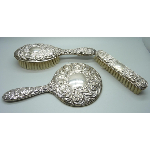 871 - A silver three piece dressing table set with embossed design, Birmingham 1980, cased