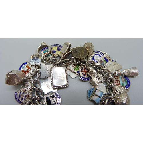 909 - A silver charm bracelet with silver and white metal charms including enamelled examples, 103g