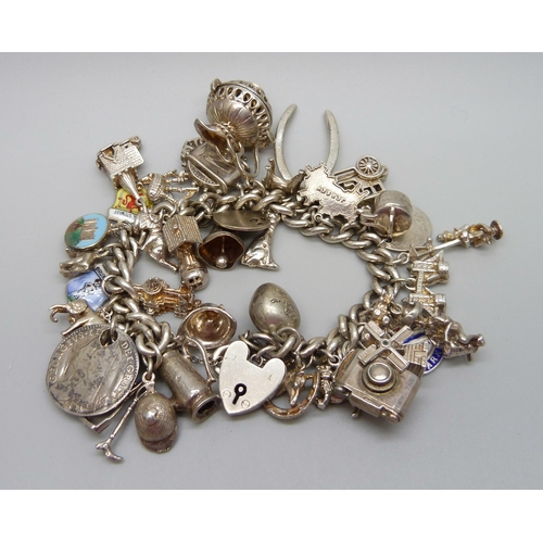 929 - A silver charm bracelet with a collection of silver and white metal charms, 114g