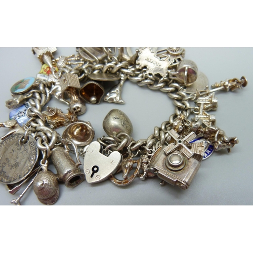 929 - A silver charm bracelet with a collection of silver and white metal charms, 114g