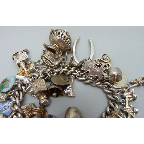 929 - A silver charm bracelet with a collection of silver and white metal charms, 114g