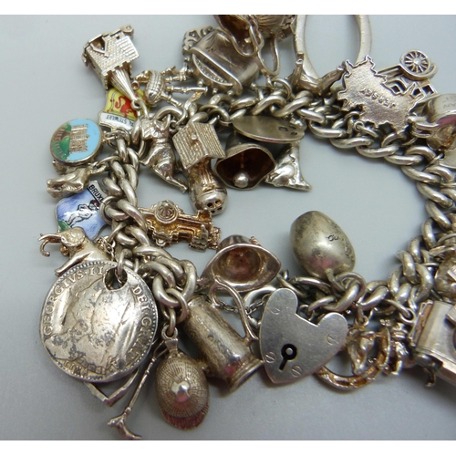 929 - A silver charm bracelet with a collection of silver and white metal charms, 114g