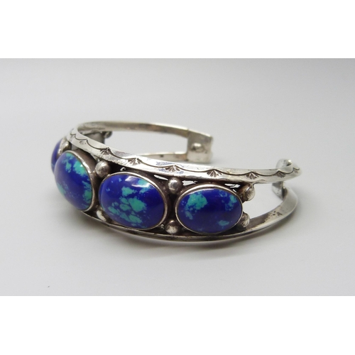 954 - A white metal bangle set with cabochon blue stones, 37g, largest stone 1.9 x 1.3cm